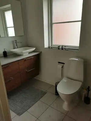 a bathroom with a toilet and a sink and a mirror at Ferielejlighed in Nibe