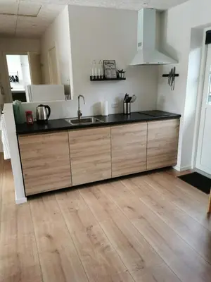 a kitchen with a black counter top and wooden cabinets at Ferielejlighed in Nibe