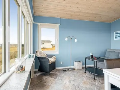 a living room with blue walls and a chair and a table at Holiday Home Nyalle - 50m to the fjord by Interhome in Struer