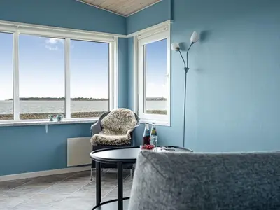 a room with a table and a chair and windows at Holiday Home Nyalle - 50m to the fjord by Interhome in Struer