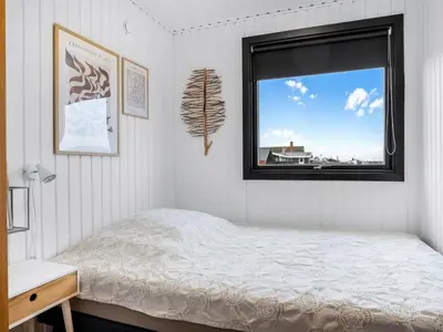 a white bedroom with a bed and a window at Holiday Home Waghn - 250m from the sea by Interhome in Harboør