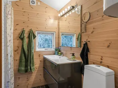 a bathroom with wooden walls and a toilet and a sink at Holiday Home Annemone - 900m from the sea by Interhome in Blokhus