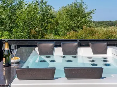 a glass table with chairs and a bottle of wine at Holiday Home Ilya - 1-7km from the sea by Interhome in Saltum
