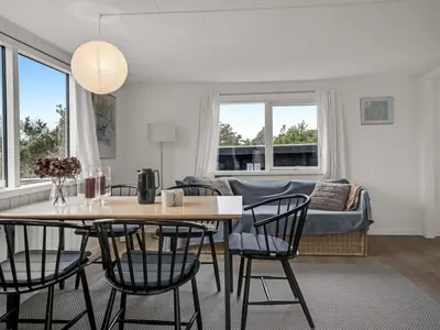 a living room with a table and chairs and a couch at Holiday Home Godja - 1km from the sea by Interhome in Blokhus