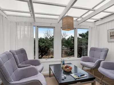 a living room with two chairs and a table and windows at Holiday Home Godja - 1km from the sea by Interhome in Blokhus