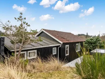 a black house with a rusty roof at Holiday Home Godja - 1km from the sea by Interhome in Blokhus