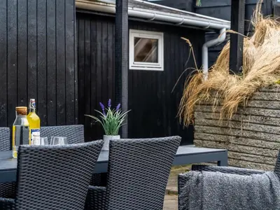 an outdoor table with chairs and a bottle of wine at Holiday Home Godja - 1km from the sea by Interhome in Blokhus