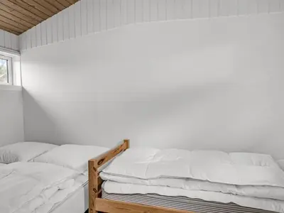 two beds in a bedroom with white walls at Holiday Home Godja - 1km from the sea by Interhome in Blokhus