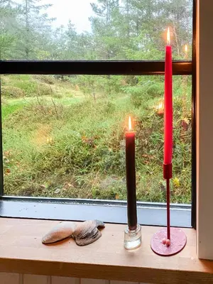 two candles sitting on a window sill in front of a window at Forest Cabin With Panoramic View Near Blokhus in Blokhus