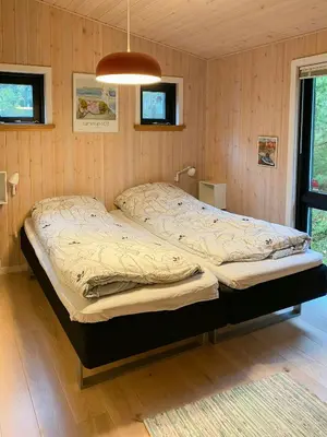 a large bed in a room with wooden walls at Forest Cabin With Panoramic View Near Blokhus in Blokhus