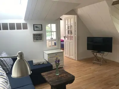 a living room with a blue couch and a tv at Kornloftet i Lodbjerg in Vestervig