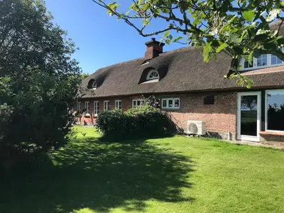 a large brick house with a grass yard at Kornloftet i Lodbjerg in Vestervig