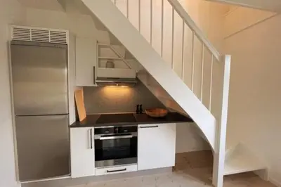a kitchen with a counter with a refrigerator and a staircase at Cozy Scandinavian Apartment in the Heart of Viborg in Viborg