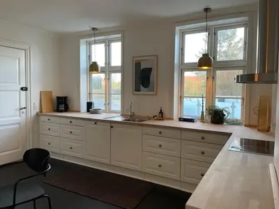 a large kitchen with white cabinets and windows at Modern Scandinavian Apartment in Viborg Centre in Viborg