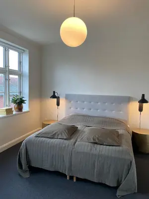 a bedroom with a large bed and a light fixture at Modern Scandinavian Apartment in Viborg Centre in Viborg