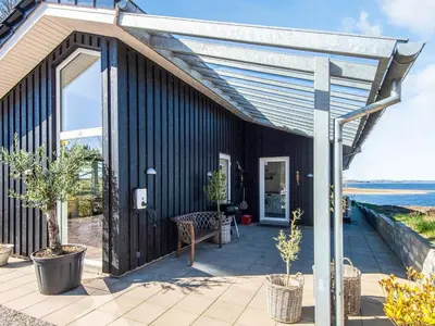 a black house with a patio with trees on it at 5 star holiday home in Løgstrup in Løgstrup