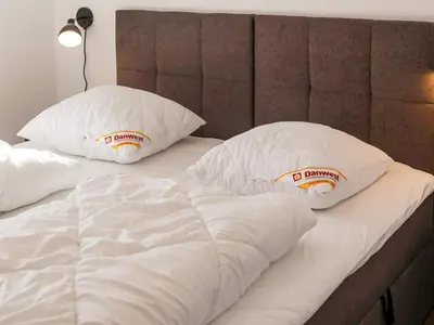 a white bed with two pillows on top of it at 5 star holiday home in Blokhus in Blokhus