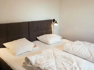 a bed with white sheets and pillows on it at 5 star holiday home in Blokhus in Blokhus