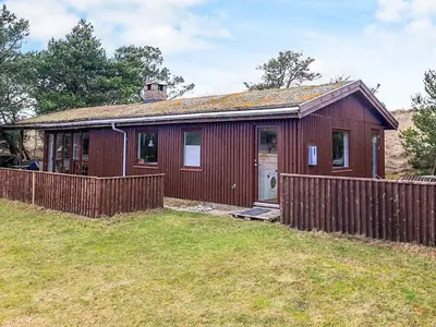 a small red house with a wooden fence at 6 person holiday home in Pandrup in Pandrup