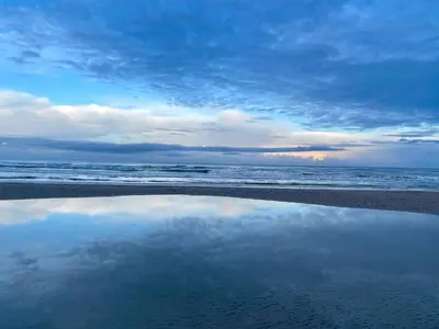 a reflection of the sky in the water on the beach at 6 person holiday home in Pandrup in Pandrup
