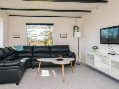 a living room with a black leather couch and a table at 5 person holiday home in Snedsted in Snedsted