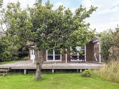 a log cabin with a picnic table on a wooden deck at 4 star holiday home in Spøttrup in Lihme