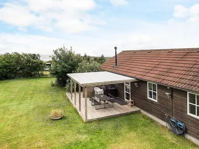 a house with a deck with a bench and a roof at 4 star holiday home in Spøttrup in Lihme