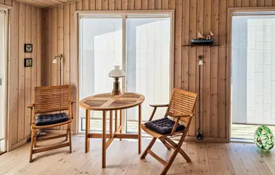 a table and two chairs in a room with windows at 3 Bedroom Cozy Home In Løkken in Løkken