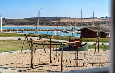 a playground with a swing set next to a body of water at Cozy Apartment In Lemvig With Sauna in Lemvig