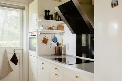 a kitchen with a stove top oven next to a window at Warm 70S Vibe Near Limfjord in Løgstør