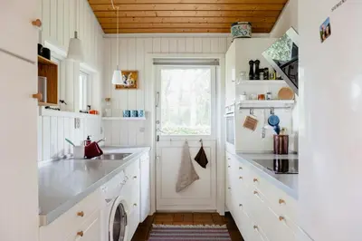 a kitchen with white cabinets and a sink at Warm 70S Vibe Near Limfjord in Løgstør