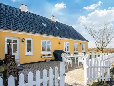 a yellow house with a table and a white fence at 4 star holiday home in Løkken in Løgsted