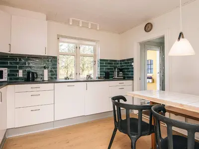 a kitchen with white cabinets and a table and chairs at 4 star holiday home in Løkken in Løgsted