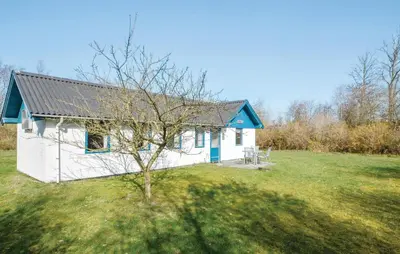 a white house with a blue roof in a field at 2 Bedroom Nice Home In Roslev in Roslev