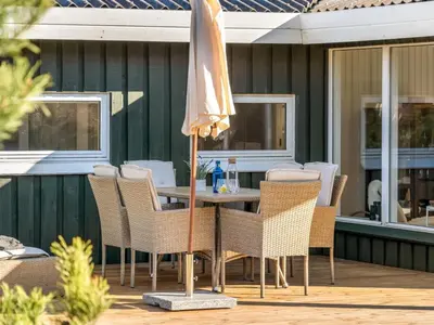 a table with chairs and an umbrella on a patio at Holiday Home Gundborg - 200m from the sea by Interhome in Saltum