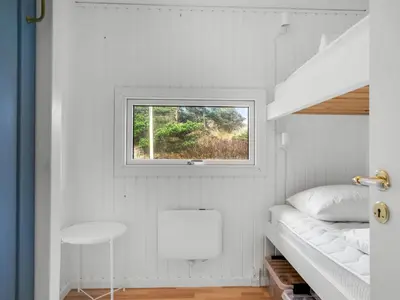 a small white bedroom with a window and a bed at Holiday Home Gundborg - 200m from the sea by Interhome in Saltum