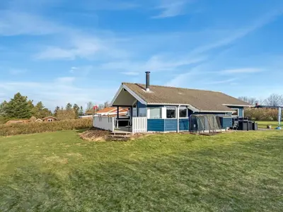 a blue and white house on a grass field at Holiday Home Anline - 600m to the fjord by Interhome in Farsø