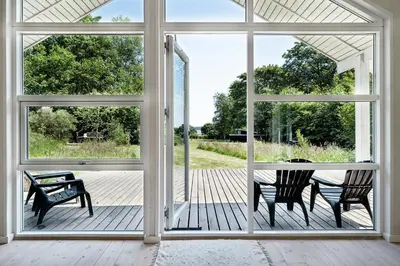 an open door to a deck with a table and chairs at Forest House With Stream By Hjarbæk Fjord in Højslev