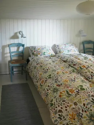 a bed with a comforter and two chairs in a bedroom at Traditional Holiday Home At Cold Hawaii in Torsted