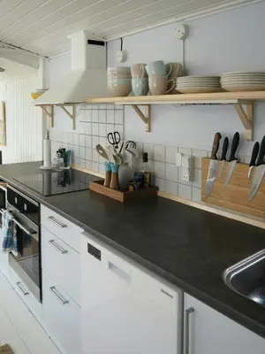 a kitchen with white cabinets and a black counter top at Traditional Holiday Home At Cold Hawaii in Torsted