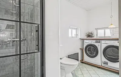 a bathroom with a toilet and a washing machine at Nice Home In Blokhus With Wifi in Blokhus