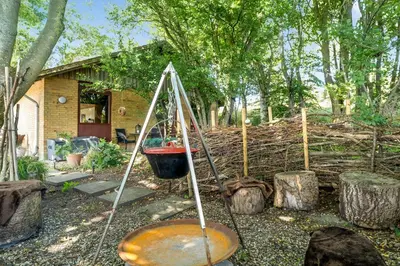 a garden with a bucket and trees and a house at Cozy Holiday Home Near Lild Strand in Frøstrup