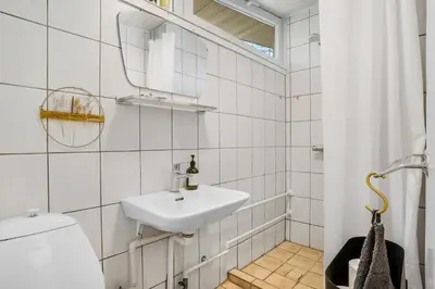 a bathroom with a sink and a toilet and a mirror at Lovely Holiday Home With Panoramic View Of The Fjord in Amtoft