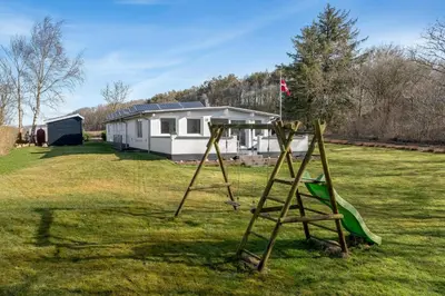 a swing set in a yard in front of a house at Holiday Home With Pool And Spa Close To The Limfjord in Roslev