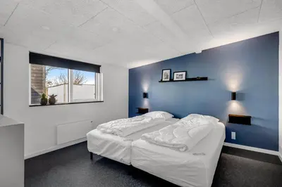 a bedroom with a bed with a blue wall at Holiday Home With Pool And Spa Close To The Limfjord in Roslev
