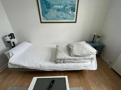 a bedroom with a bed with white sheets and a table at Cozy base near the cathedral in Viborg