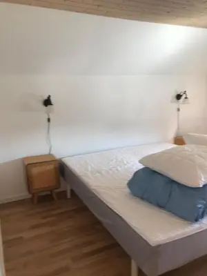 a bed in a room with a white wall at Townhouse centrally located close to Jesperhus in Nykøbing Mors