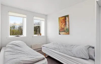a white bedroom with a bed and two windows at 2 Bedroom Stunning Home In Øster Assels in Øster Assels