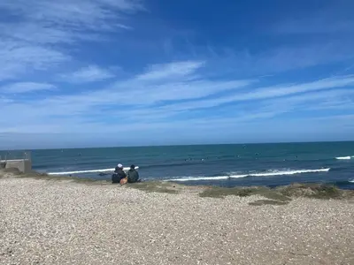 two people sitting on the beach looking at the ocean at Surfreservatet i Nationalpark Thy in Hanstholm