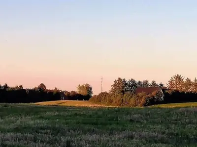 a field of grass with a barn in the distance at 5 star holiday home in Løkken in Løkken